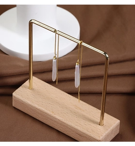 Detail of long gold box chain earrings with natural white baroque drop pearls on a stand