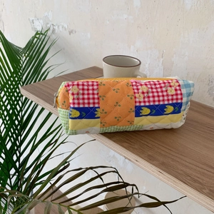 Detailed close-up of quilted floral patchwork stationery bag with zipper on wood shelf