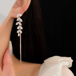 Close-up of silver-tone leaf earrings with sparkling rhinestones and long chain tassels