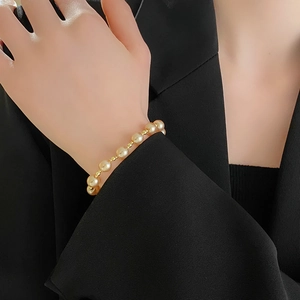 Detail of French style gold pearl bracelet on wrist featuring elegant metallic luster beads