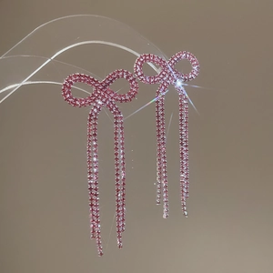 Detailed close-up of pink rhinestone bow earrings with long tassel fringe and shimmer