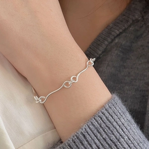 Close-up of minimalist sterling silver wavy chain bracelet worn on a female wrist
