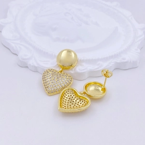 Detail of heart-shaped earrings in gold finish with micro-set sparkling white zircons