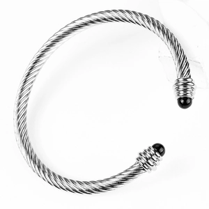 Macro detail of silver twisted cable cuff bracelet with black bead end caps