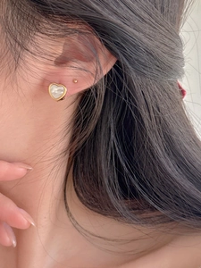 Close-up of heart-shaped shell earrings with gold plating on ear for realistic fit