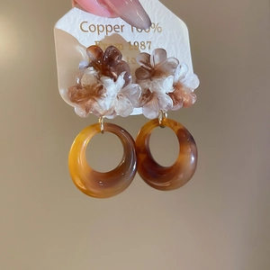 Close-up of retro resin flower earrings with amber textured hoops and copper base
