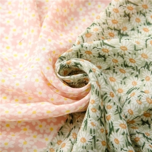 Detail of soft floral printed fabric showing delicate daisy patterns and woven texture