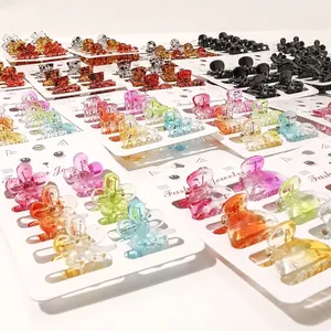 Colorful mini hair claw clips in various shapes like flowers and hearts on a display card