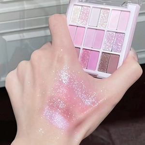 Close-up of 18-color pink eyeshadow palette with matte and shimmer swatches on skin