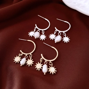 Detail of gold and silver sun star charm earrings with baroque pearls on silk