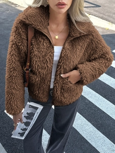 Detail view of brown faux fur zip jacket paired with grey jeans on a city street