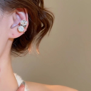 Close-up of a silver ear cuff with two sparkling zircons worn on the ear bone detail