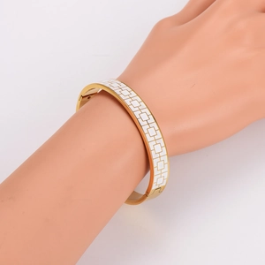 Detail of gold plated stainless steel bangle with white enamel checkered patterns