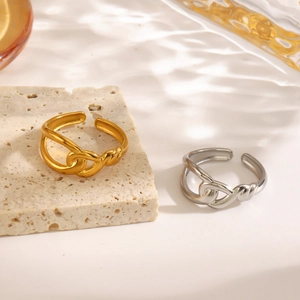 Minimalist intertwined knot ring in gold and silver finish on natural stone background