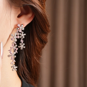 Close-up of model wearing sparkling flower tassel earrings with pink and clear cubic zirconia