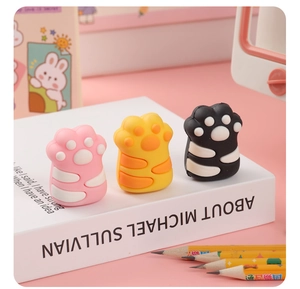 Detail of cute cat paw pencil sharpeners in pink yellow and black on a book