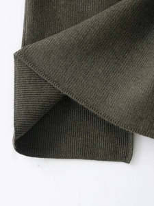 Gros plan sur la texture tricotée côtelée vert olive de l'ensemble gilet et jupe chic