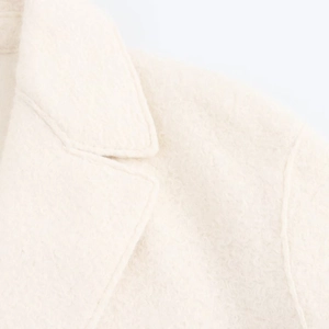 Close-up of elegant off-white wool coat featuring lapel collar and detailed fabric texture