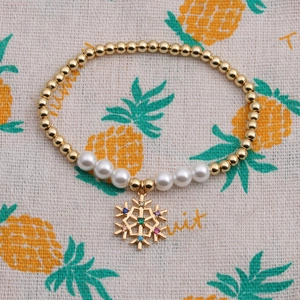 Bracelet élastique doré avec perles blanches et pendentif flocon de neige en cristal