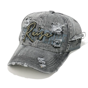 Macro detail of washed grey denim cap with embroidery, distressed holes and metal rings