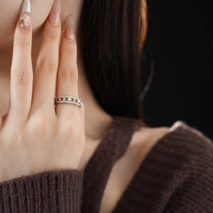 Detail of wavy zircon pearl ring on finger with hollow design in premium silver finish