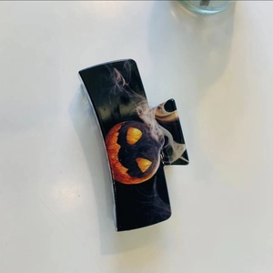 Detail of black Halloween hair claw clip with orange pumpkin and smoky patterns