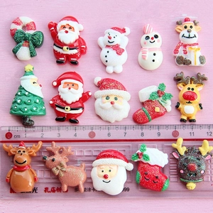 Macro shot of assorted Christmas resin charms like Santa and Reindeer with ruler for scale