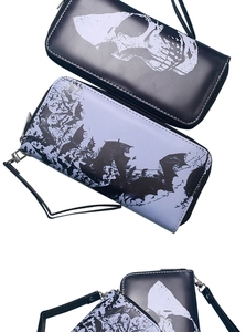 Detail view of long zipper wallets with gothic skull and bat patterns on leather texture