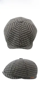Detail of grey plaid newsboy cap showing octagonal stitching and brown leather label