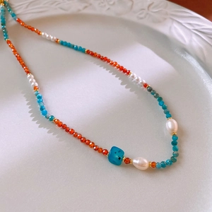 Detail of beaded necklace with orange stones, blue turquoise and white freshwater pearls
