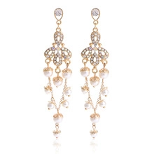 Detailed macro of gold tassel earrings with intricate white pearls and rhinestones