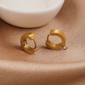 Polished gold hoop earrings in chunky round design resting on soft champagne silk fabric