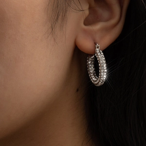 Detailed close-up of a silver-toned hoop earring featuring brilliant pave-set rhinestones