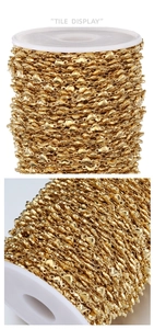 Macro view of 18k gold plated stainless steel heart link chain on white plastic spool