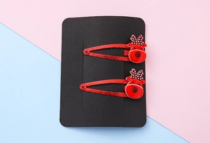 Detail of red glitter Christmas reindeer hair clips with polka dot antlers on a black card