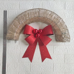 Detailed view of 50cm gold glitter Christmas arch wreath with a large red bow and berries