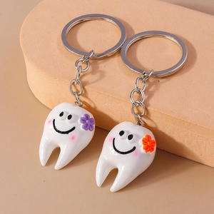 Simpatici portachiavi a forma di dente con fiori viola e arancioni su base beige