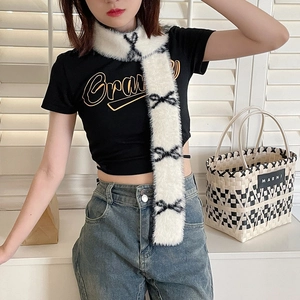 Close-up of white plush scarf featuring black bow patterns worn by a model