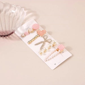Détail d'un lot de 5 barrettes roses avec perles, strass et motifs de fleurs et cœurs