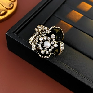 Macro shot of vintage floral brooch with black enamel, sparkling crystals and a center pearl