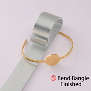 Detailed view of golden open bangle with round disc on a metal bending tool