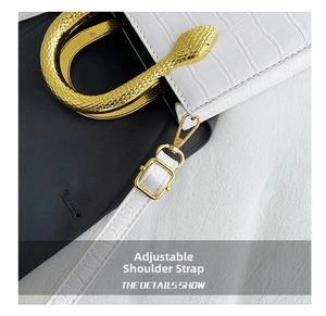 Detail of white crocodile texture bag with golden snake handle and adjustable strap