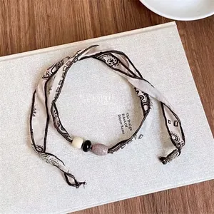 Dettaglio della collana in nastro Paisley boho con perle variegate effetto marmo