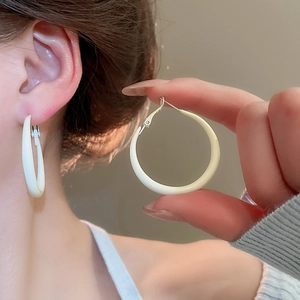 Detailed view of white minimalist hoop earrings with a smooth glossy finish on model