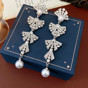 Macro detail of silver tassel bow earrings with rhinestones and pearls on blue box