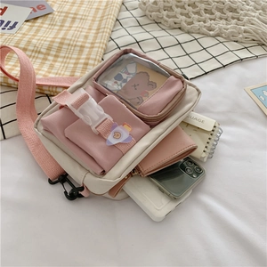 Detail of a pink and white canvas crossbody bag with multiple pockets and cute logo