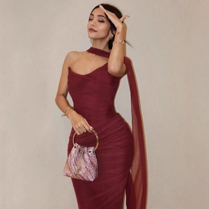 Detail of elegant wine red off-shoulder ruched dress with a sequined purple handbag