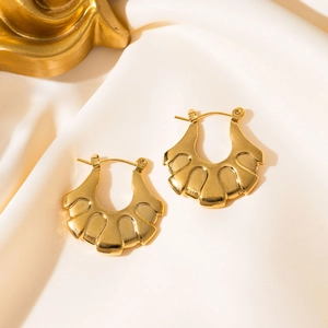 Detailed view of gold fan-shaped stainless steel earrings on a silk fabric background