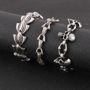 Punk style stainless steel bracelets with skull and anchor charms on a black display