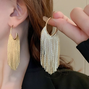 Vue détaillée des boucles d'oreilles dorées avec anneau en C et chaînes métalliques fluides